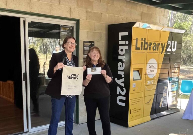 Self-Service Checkout 14 Librarians holding items in front of Blue Mountains Library remoteLocker.