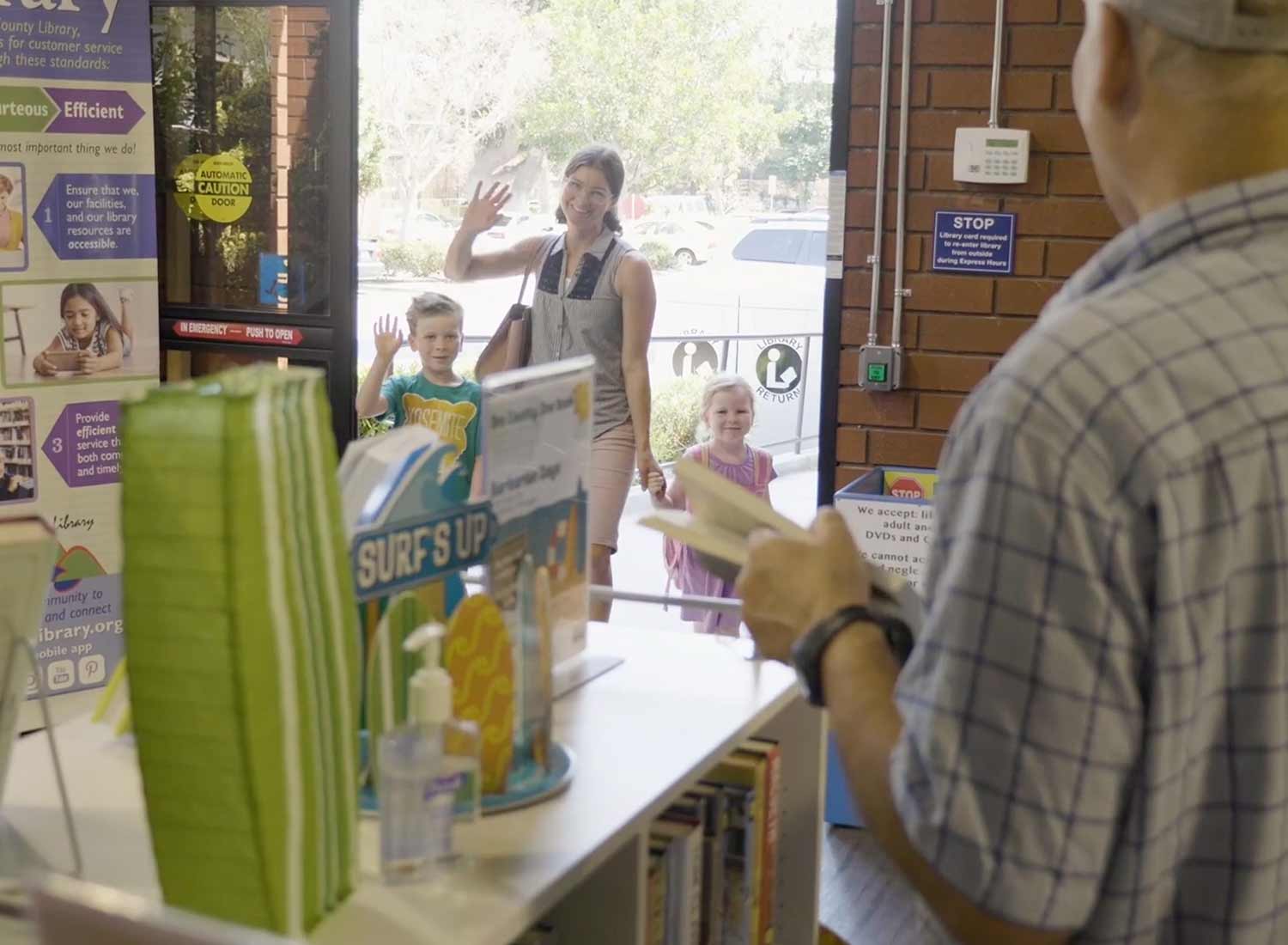 Occupancy + Compliance 1 Mother and chrildren waving at librarian from library door