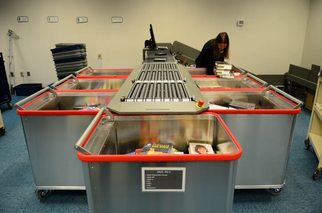 Bibliotheca flex AMH automated materials handling system sorting returned library items into bins at Forsyth County Public Library.